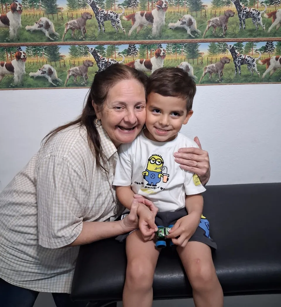 La Dra. Rosa Marín abraza sonriente a un nene sentado en la camilla del consultorio.